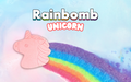 A unicorn-shaped bath bomb with a colorful rainbow mane and tail, displayed against a blue background with the product name 'Rainbomb Unicorn' at the top.