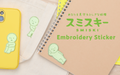 Image shows the three variations of product SMISKI Embroidery Sticker written in both English and Japanese. (Left) depicts a yellow phone case with SMISKI Embroidery Sticker "Hugging Knees" (Middle) shows SMISKI "Peeking" on a white canvas bag. (Right) shows SMISKI "Lounging" Embroidery Sticker on a tan spiral bound notebook under the image's text.